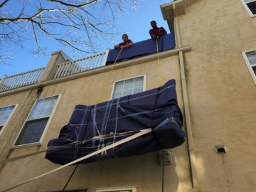 Heavy headboard being hoisted to balcony on the roof