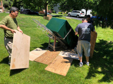 Our team lays plywood on the ground to help the dolly through the grass.